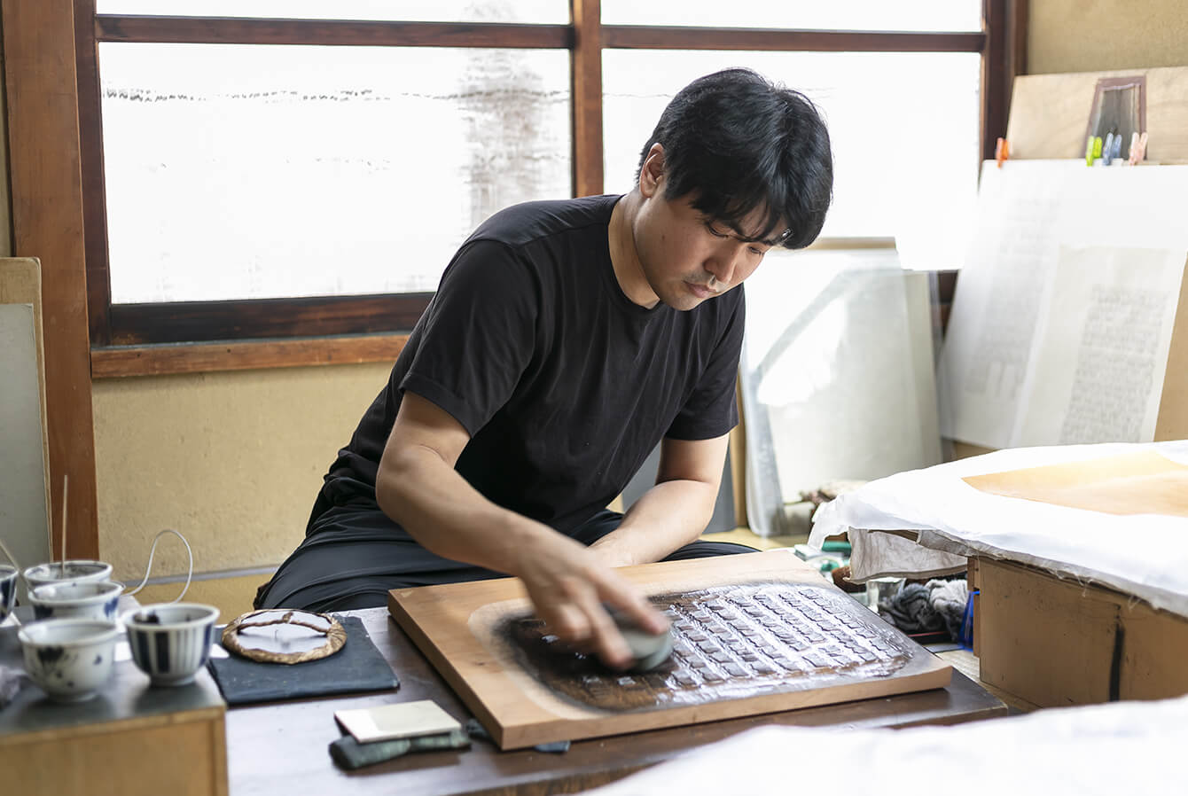 A printing artist at work on the second floor of the studio. The work proceeds silently, at a good pace, but with precision and confidence.